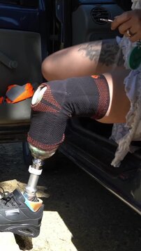 Independent woman with a prosthetic leg getting out of her car. Detail shot of her bionic limb as she exits the vehicle and locks the door