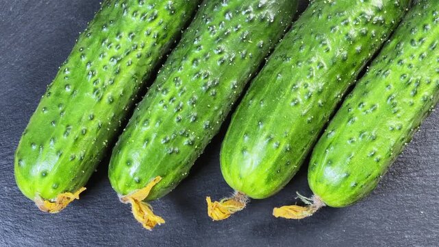 Freshly harvested cucumbers on black slate plate on rustic table
