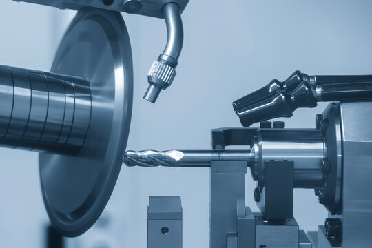 High-precision CNC grinding machine manufacturing an end mill tool with an abrasive wheel.