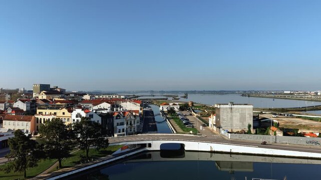 High-quality aerial wide shot of the picturesque city of Aveiro, Portugal. The video captures the calm waters of the Ria de Aveiro lagoon, salt pans, and urban canals winding next to traditional house