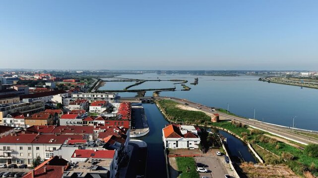 High-quality aerial wide shot of the picturesque city of Aveiro, Portugal. The video captures the calm waters of the Ria de Aveiro lagoon, salt pans, and urban canals winding next to traditional house