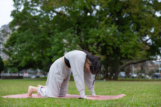 Woman doing cat cow yoga pose outdoors