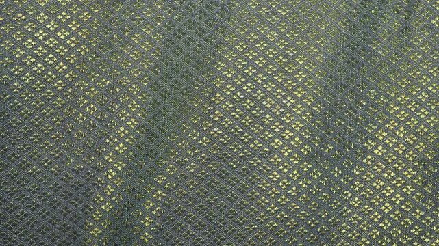 Curtains featuring an intricate diamond pattern known as lai khao lam tad combine geometric shapes with shimmering gold threads.
