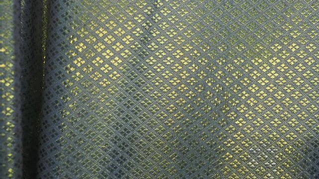 Curtains featuring an intricate diamond pattern known as lai khao lam tad combine geometric shapes with shimmering gold threads.