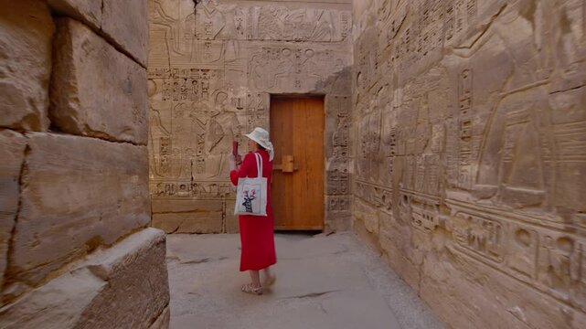 A woman in a red dress exploring the ruins of the Karnak Temple, Luxor, Egypt.