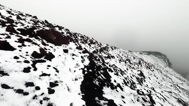 Snow Covered Mountain Ridge in Ecuador Andes with Fog, Black Volcanic Rocks and Remote High Altitude Paramo Wilderness Landscape