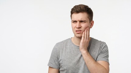 Obraz premium Young man touching cheek suffering from severe toothache pain on white background