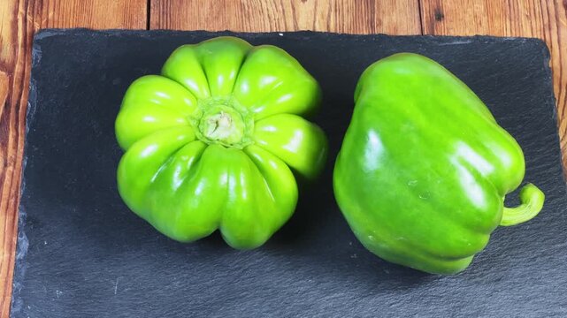 Fresh green bell peppers on a black slate flat plate