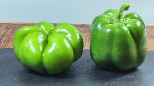 Fresh green bell peppers on a black slate flat plate