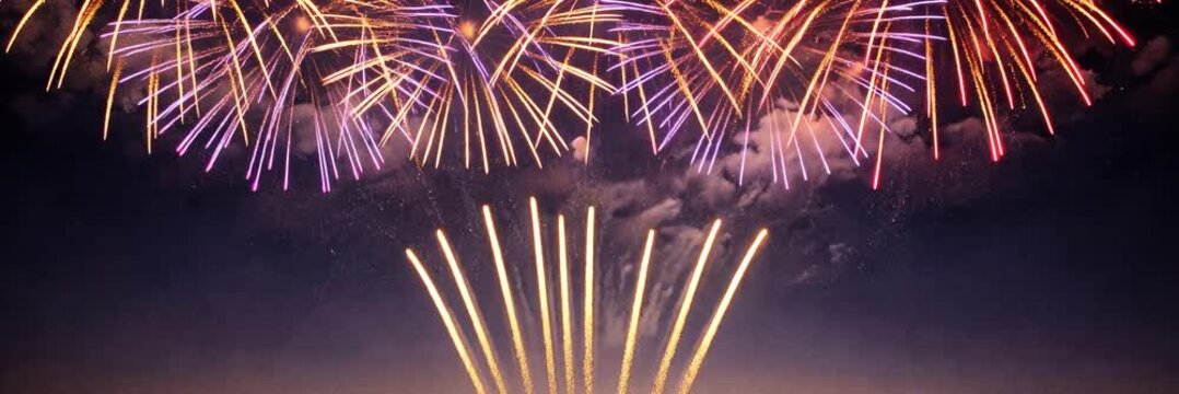 Colorful fireworks illuminate clouds across the night sky during a festive celebration, animated website banner with copy space below