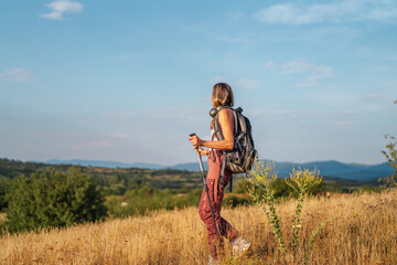 Obraz premium Woman hiking in nature observing mountain view at sunset