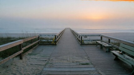Naklejka premium Empty wooden beach boardwalk leading into foggy ocean sunrise with soft pastel sky