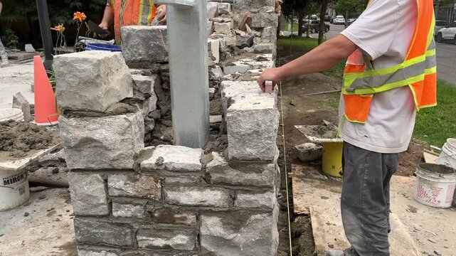 Construction worker building natural stone wall outdoors