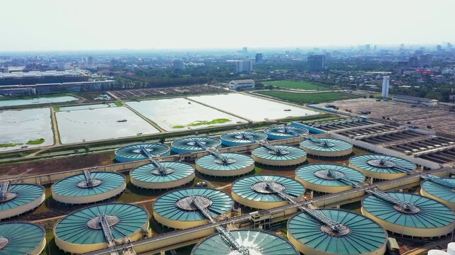 Large industrial wastewater treatment plant processes water within sprawling urban setting, showcasing advanced environmental technology and sustainable water management solutions.