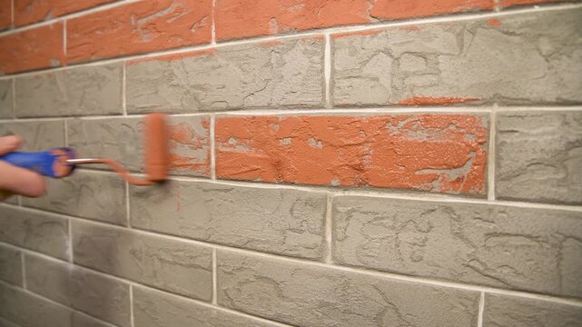 Painting a decorative brick-shaped wall red. Painting and finishing work.