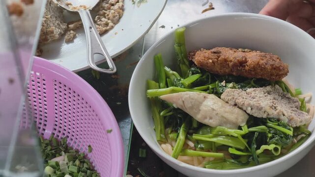 Close up of street food vendor adding crab meat topping to a bowl of Vietnamese rice noodle soup ( Canh Bun )