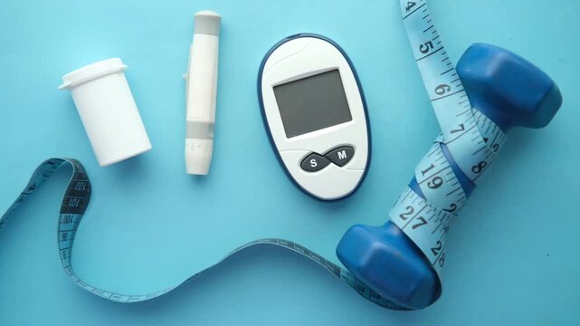 Diabetes management kit with glucose meter, lancet device, dumbbell, and measuring tape on blue background