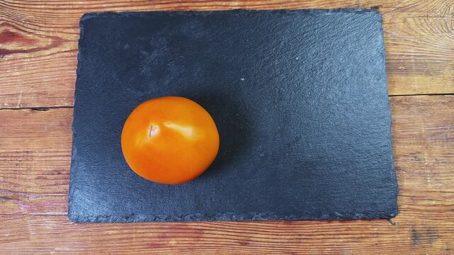 Laying out orange color tomatoes to black slate flat plate