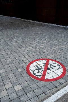 A red prohibition symbol for bicycles forms a bold pavement marking on an urban street, making traffic regulation and safety immediately visible