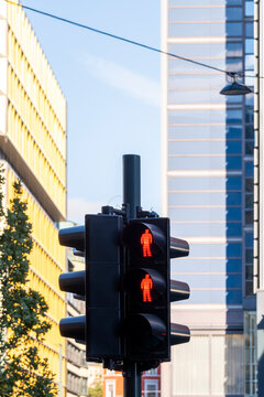 Red pedestrian signals and traffic lights stop movement at an urban street intersection, framed by contemporary buildings and a clear visual language of safety