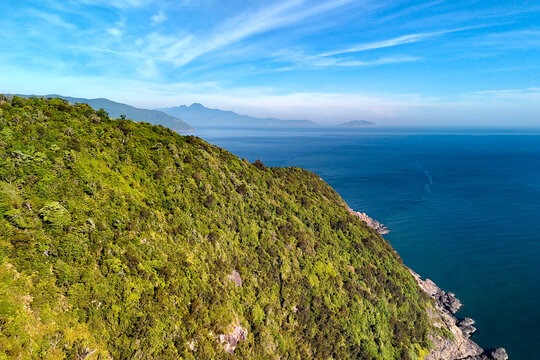 Green hillsides meet the vast blue sea under a clear sky in this scenic coastal landscape located on the Son Tra Peninsula in central Vietnam at daylight