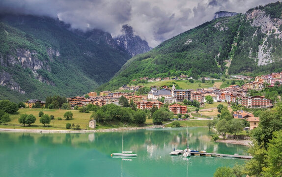 lake of Molveno in Brenta Dolomites in Italy with village at the edge of beautiful turquoise water mountains background under cloudy sky