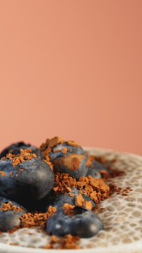 Macro shot of chia pudding with blueberries and cocoa powder in a cup on terracotta background. Healthy dessert for cafe menu, social media stories template, mobile wallpaper and wellness advertising.