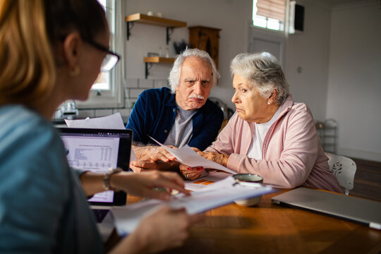 Senior couple reviewing bills with financial advisor at home
