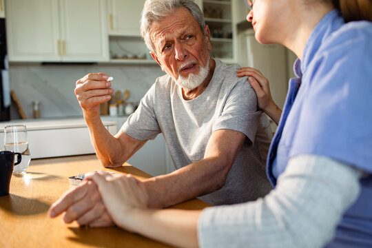 Caregiver helping senior man with medication at home