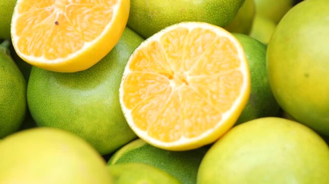 Close up of fresh green oranges with one cut in half revealing juicy pulp and segments