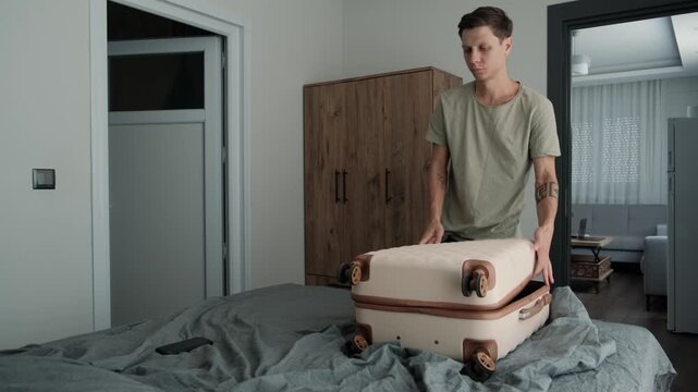 Temporary living and relocation. Man packing clothes into suitcase in rented apartment before moving, preparing belongings for another temporary home
