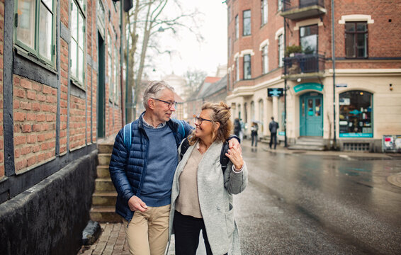 Senior couple walking arm in arm on a rainy city street