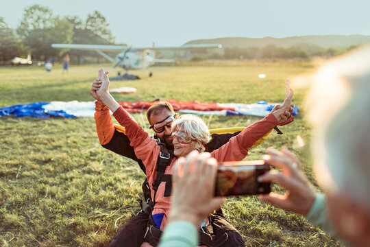 Senior woman celebrates tandem skydiving landing at airfield