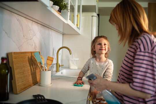 Mother and daughter cleaning kitchen counter at home