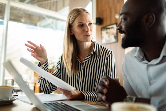 Two coworkers discussing documents at a coffee shop