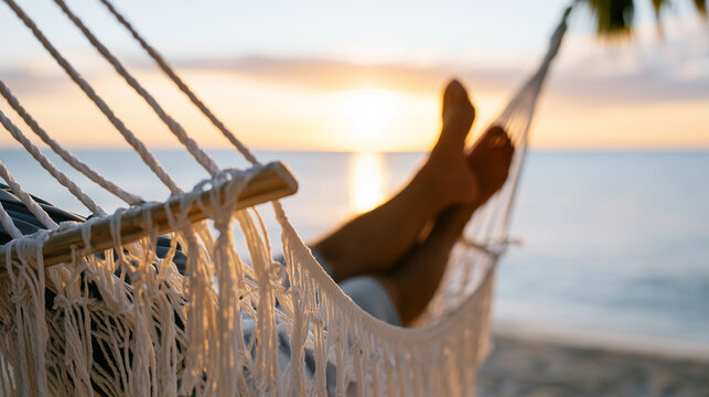 Relaxing in a white hammock on a tropical beach at sunset with a beautiful ocean view.