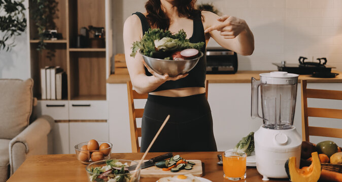Woman preparing green smoothie in bright kitchen with fresh fruits and vegetables, healthy eating lifestyle moment in natural daylight