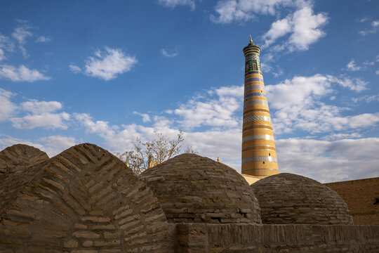 Visit to the unique minaret of Islam Khodja medersa in Khiva, Uzbekistan under blue sky and scattered clouds