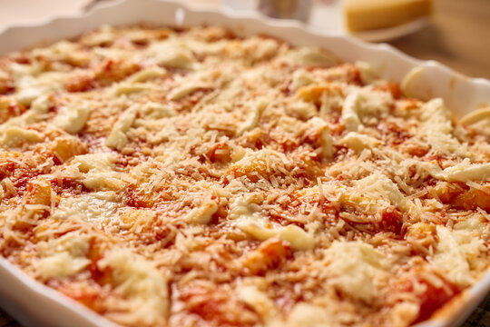 Gnocchi in tomato sauce topped with mozzarella and grated cheese in baking dish