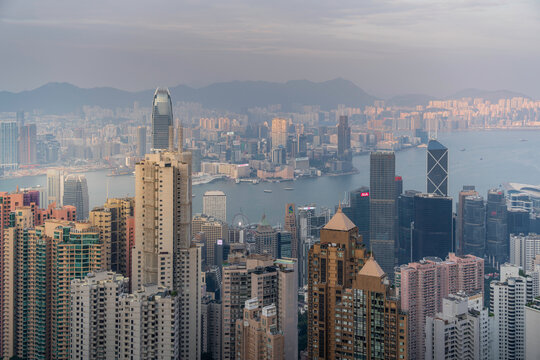 View of Hong Kong skyline from Victoria Peak at sunset with city lights appearing over Kowloon Peninsula and surrounding mountains