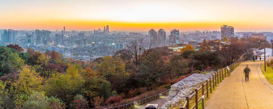 View of Seoul skyline from N Seoul Tower during sunset in autumn showing city lights and park path in Yongsan District