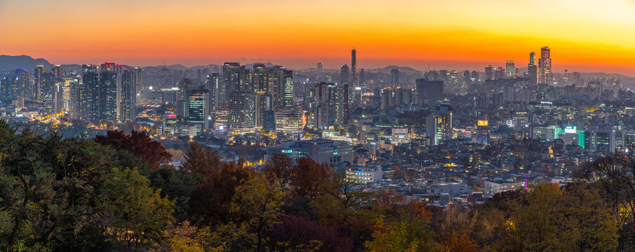 View of Seoul skyline from N Seoul Tower in autumn at dusk with bright city lights and a colorful sky