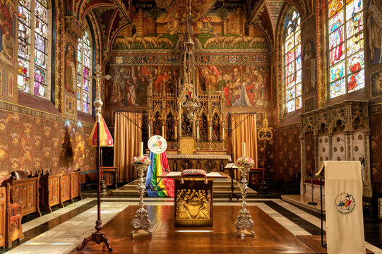 Central nave of Holy Blood chapel shows stained-glass window and altar in Bruges, Belgium