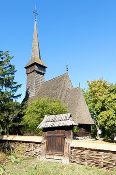 Traditional wooden church design from Maramures with a high spire and rustic fence located in a museum in Bucharest
