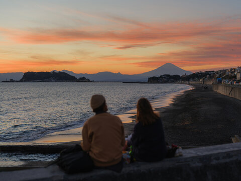Man and woman looking at mount Fuji and the sea at sunset 