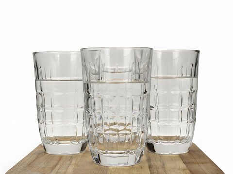 Three clear glasses of water on a wooden board for hydration and refreshment, isolated on white background