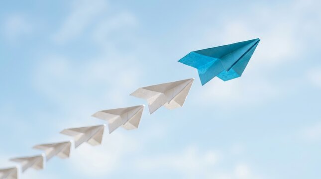 Blue paper airplane leading a line of white paper airplanes against a clear blue sky, symbolizing leadership, innovation, and breaking away from the norm, Professional Commercial Photography