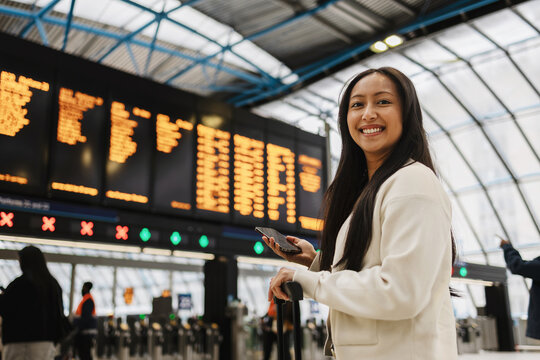 Woman smiling at station departure board