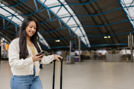 Traveler checking smartphone awaiting departure in airport terminal