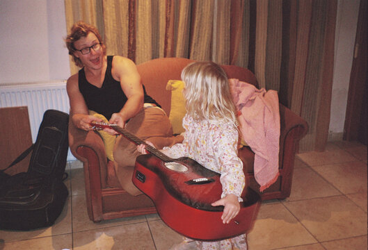 Father and Daughter Play Guitar in Living Room During Evening